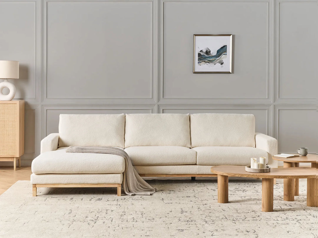 Beige sectional sofa in a living room with wooden coffee table and decorative items.