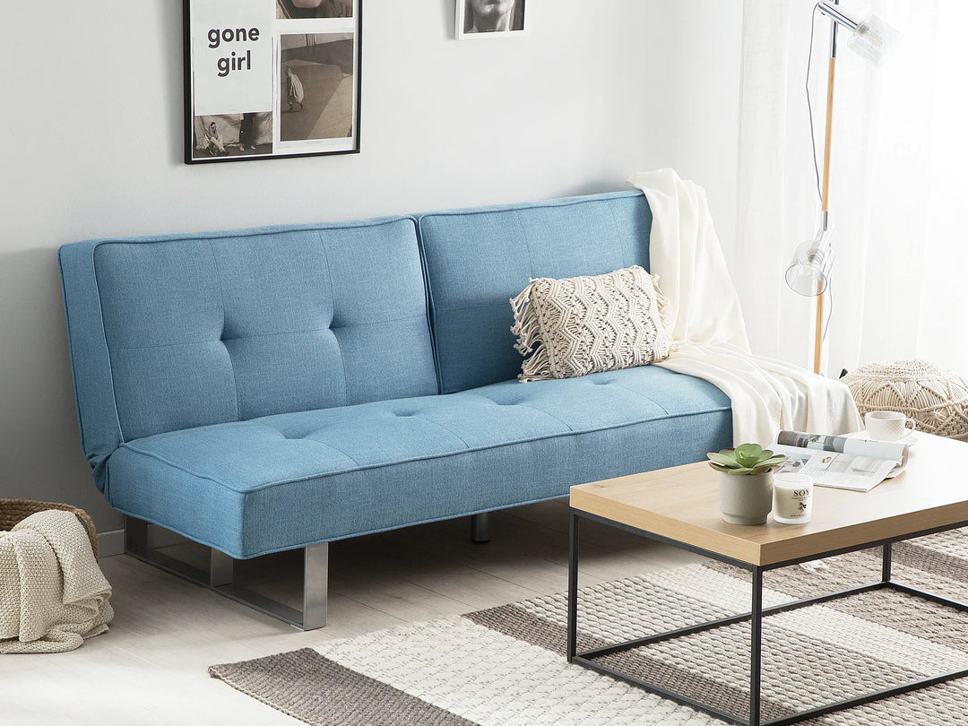 Blue sofa bed in a living room with a coffee table and decor items.