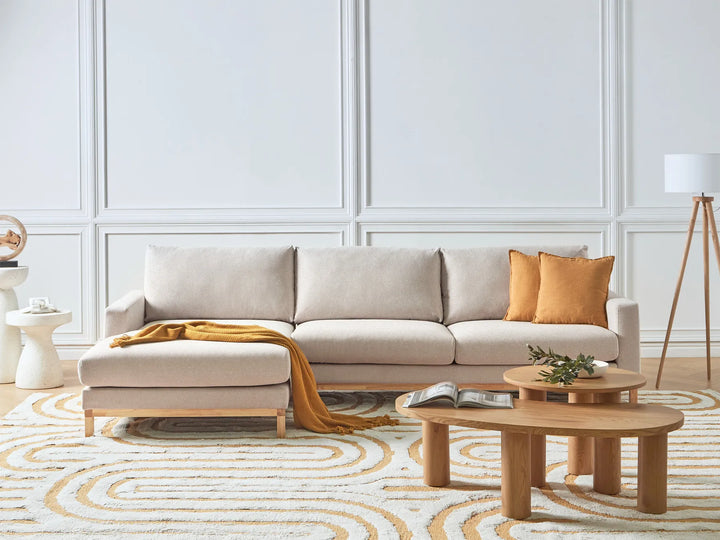 Modern living room with a beige sectional sofa, wooden coffee tables, and decorative elements.