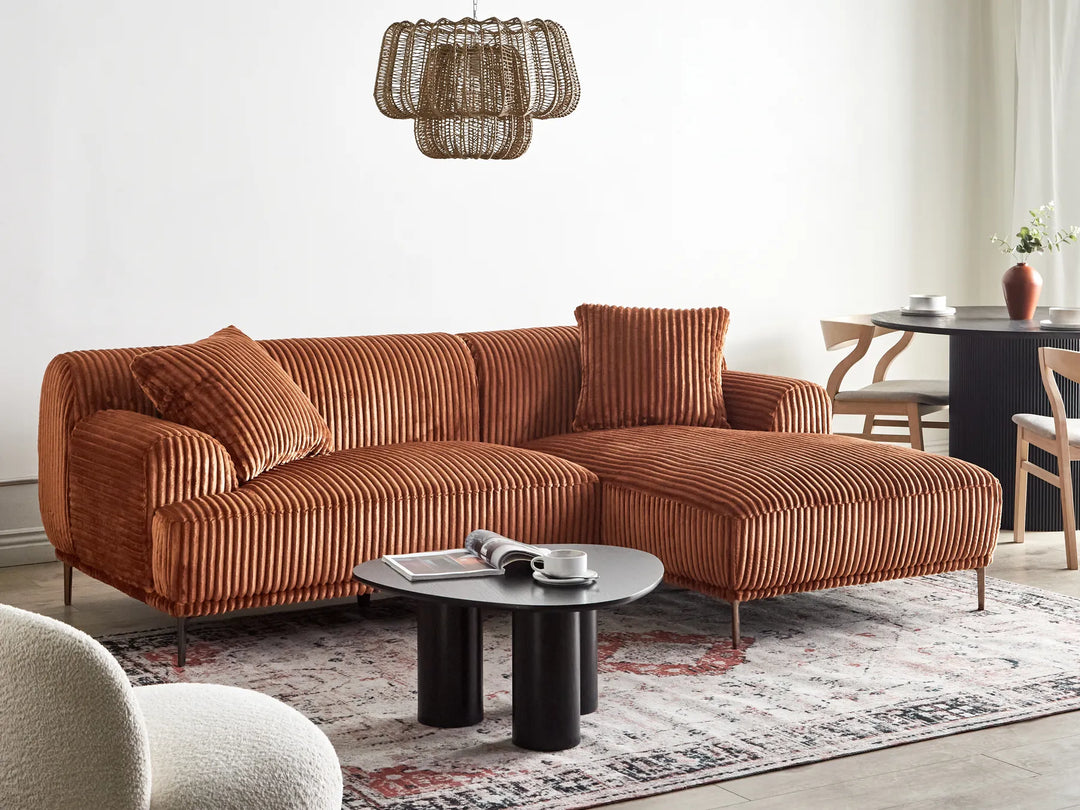 Brown sectional sofa in a living room with a coffee table and decorative items.