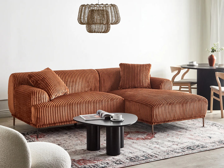Brown sectional sofa in a living room with a coffee table and decorative items.