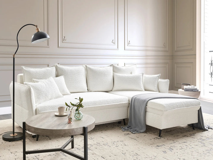 Modern living room with a white sectional sofa, coffee table, and decorative items.