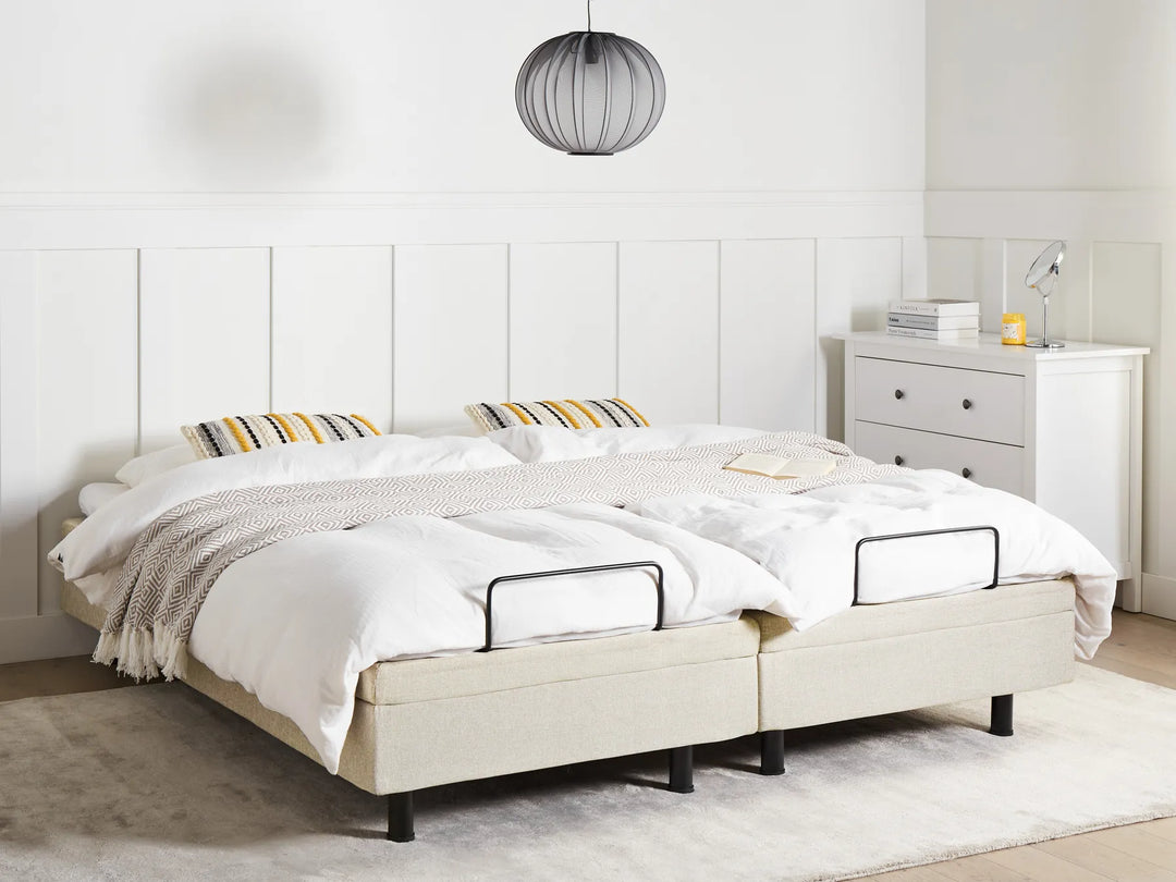 Beige adjustable bed in a room with white walls and a nightstand.