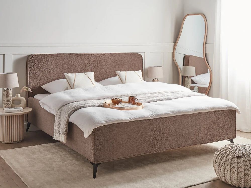 Neatly made bed with white bedding and a brown headboard in a bedroom setting.