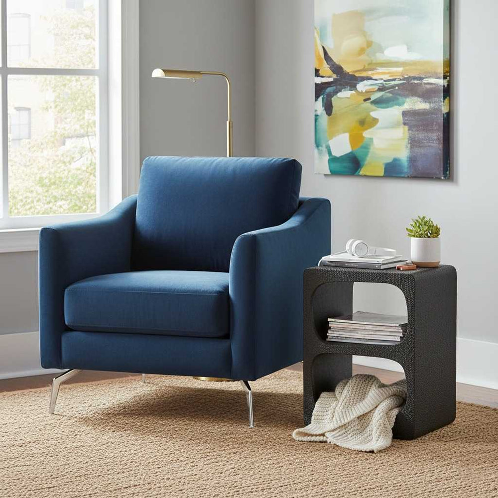 Blue armchair in a room with a side table and abstract painting