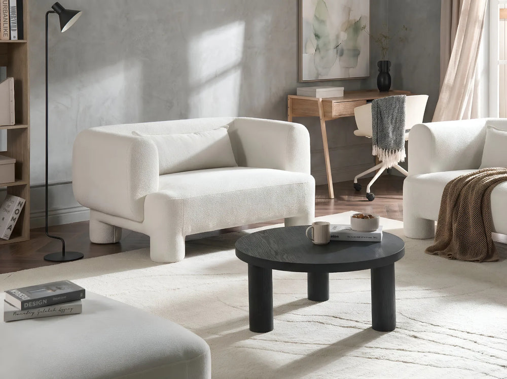 Modern living room with white armchairs, a black coffee table, and a desk.