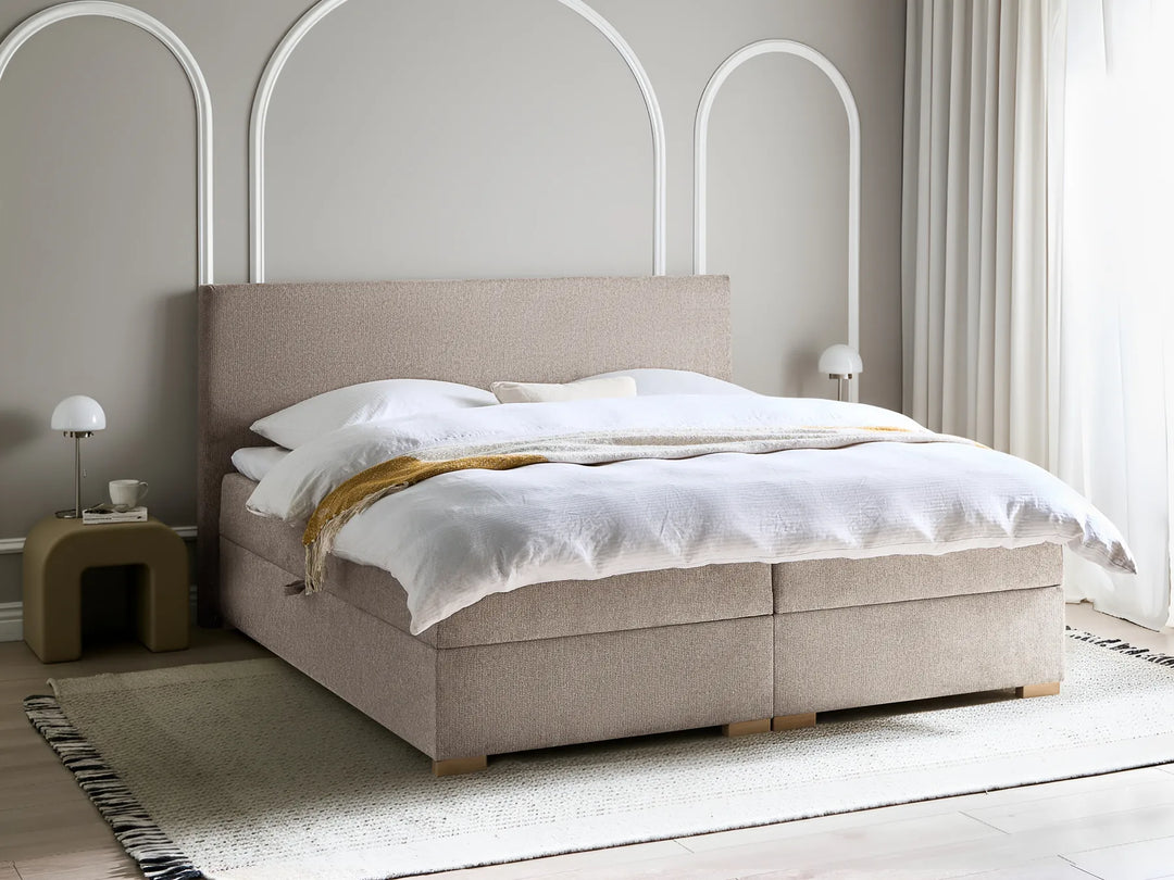 Beige upholstered bed with white bedding in a modern bedroom setting.