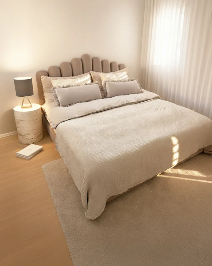 Neatly made bed with beige bedding in a bedroom setting.