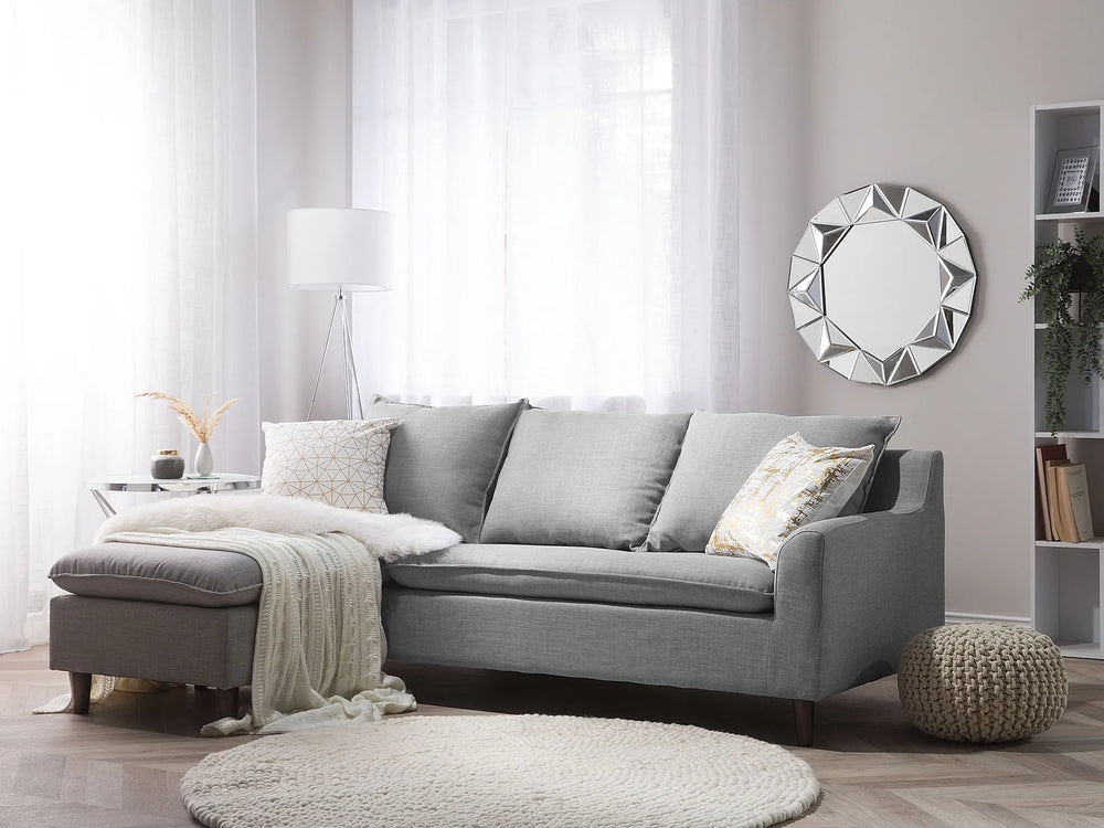 Gray sectional sofa in a living room with decorative pillows and a mirror on the wall.