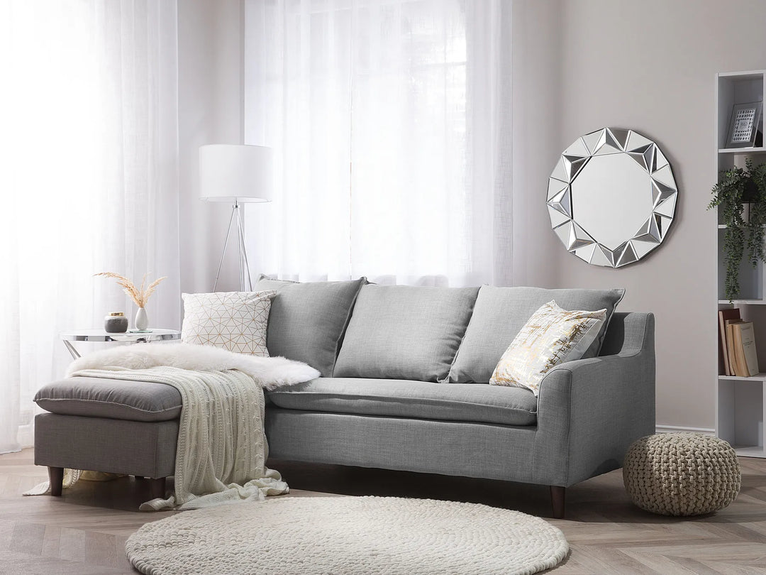 Gray sectional sofa in a living room with decorative pillows and a mirror on the wall.