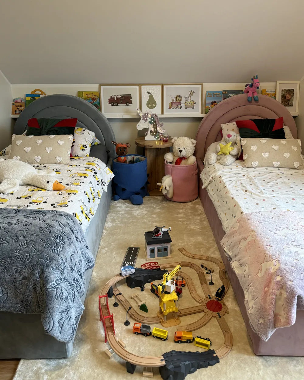 Children's bedroom with two beds, toys, and a toy train set on the floor.