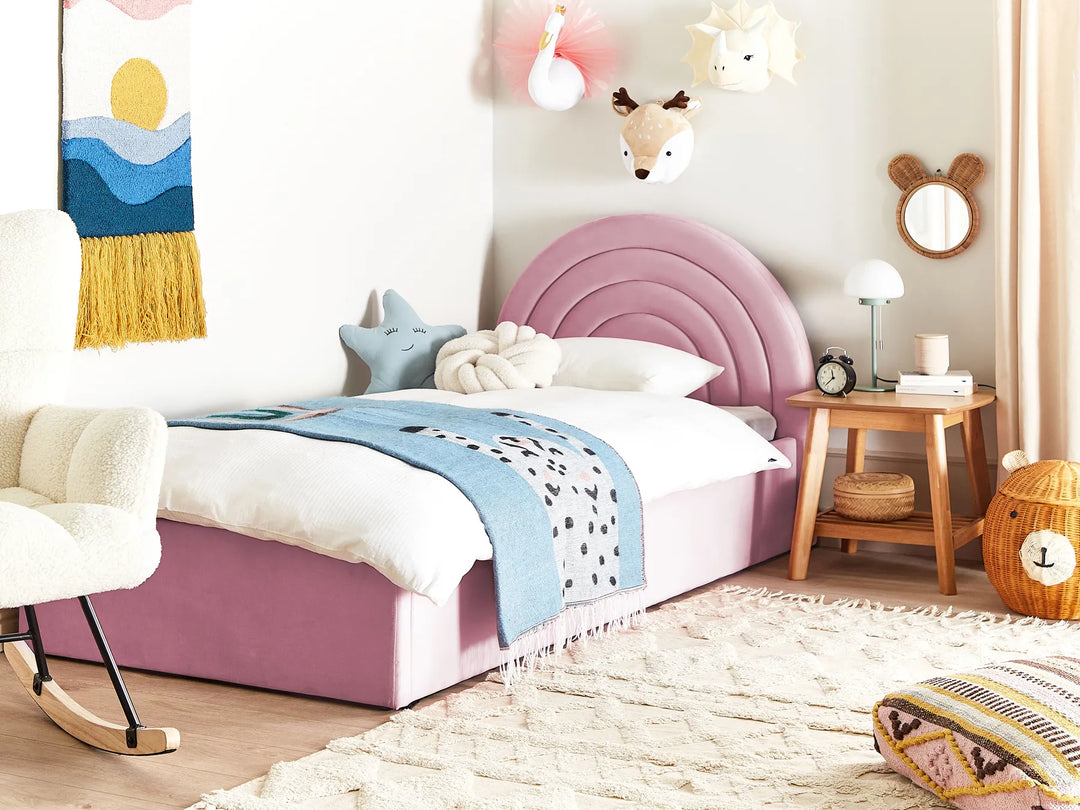 Children's bedroom with pink bed, wooden nightstand, and decorative items.