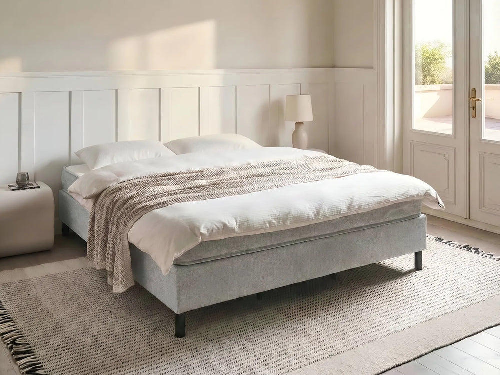Gray upholstered bed with white bedding in a bright bedroom