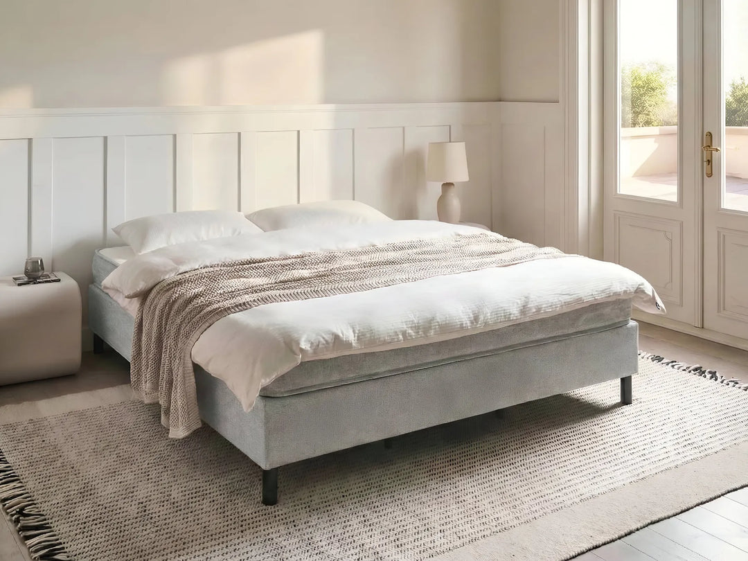 Gray upholstered bed with white bedding in a bright bedroom