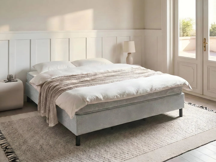 Gray upholstered bed with white bedding in a bright bedroom