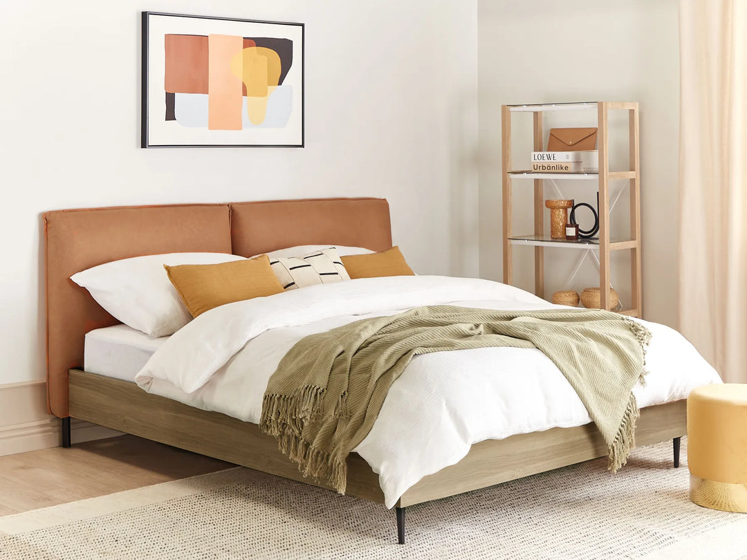 Bedroom with a bed featuring a brown headboard, white bedding, and a green throw blanket. A shelf with decor items is in the background.