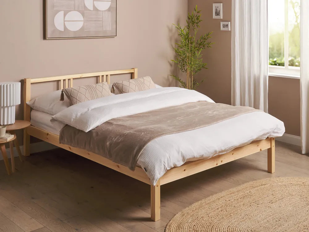 Wooden bed with bedding in a room with a window and plant