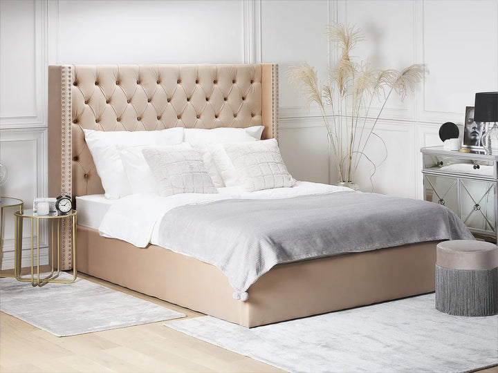 Beige upholstered bed with white bedding in a bedroom setting.