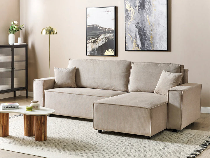Beige sectional sofa in a living room with abstract art on the wall.