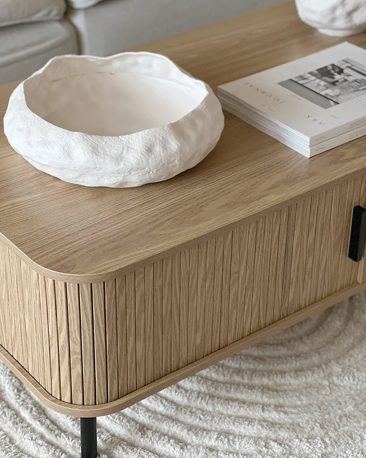White textured bowl on a wooden side table with a book in the background