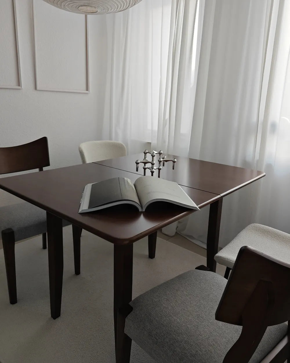 Dining room with a wooden table and chairs, featuring an open book on the table.