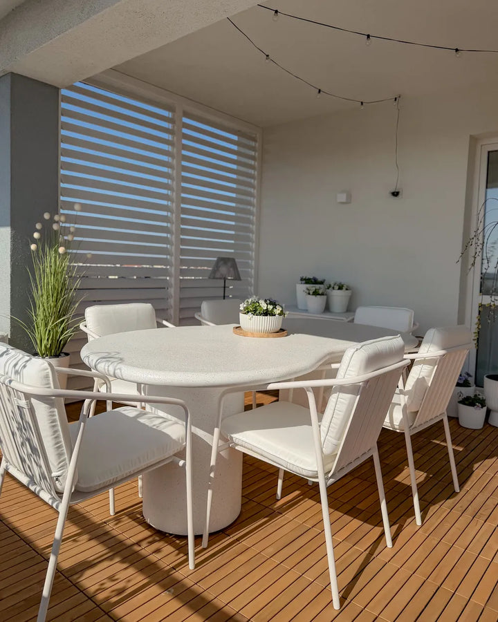 Outdoor dining area with white table and chairs on a wooden deck.