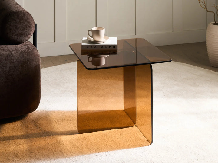 Modern glass coffee table with a cup and saucer in a living room setting.