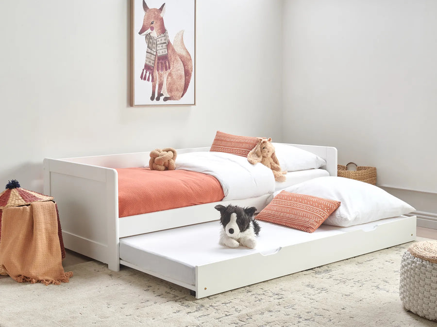 Children's bedroom with a white bed and pull-out trundle, featuring teddy bears and a dog.