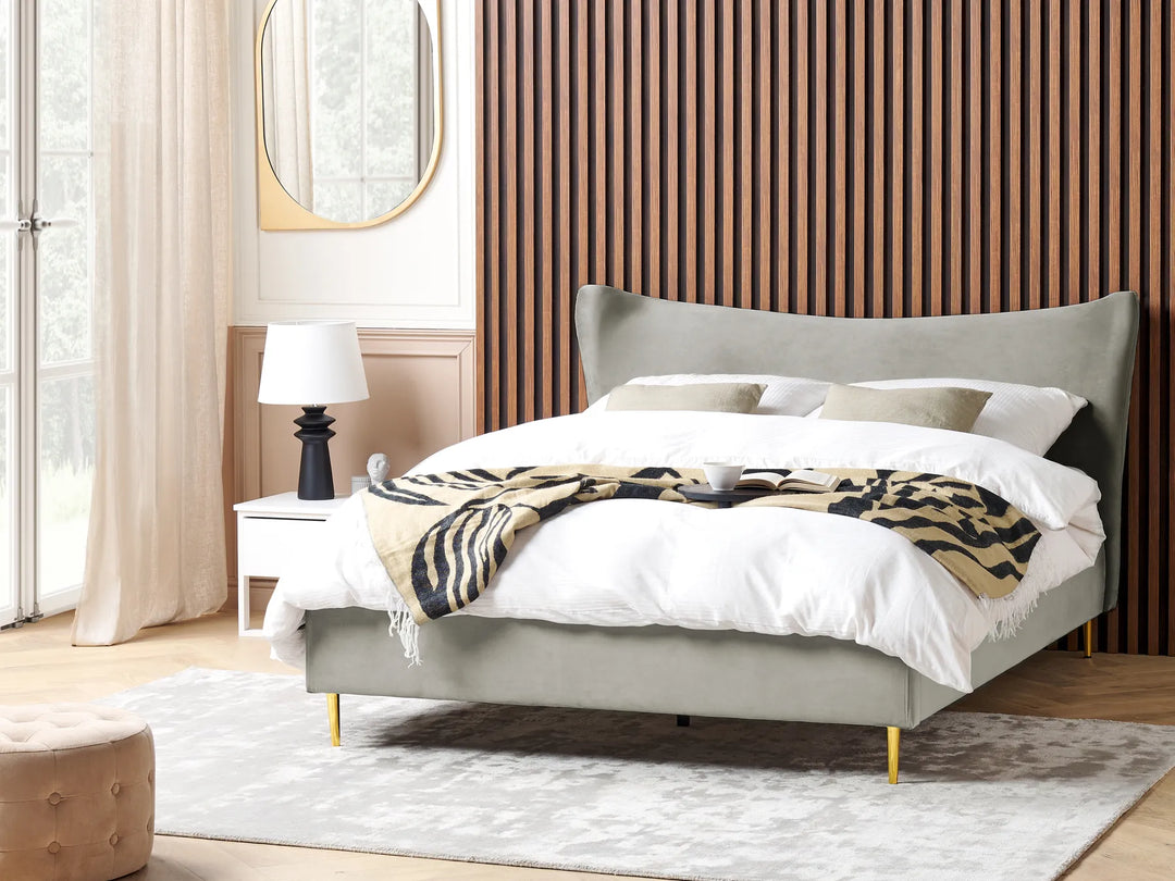 Gray upholstered bed with white bedding and a patterned throw in a bedroom setting.