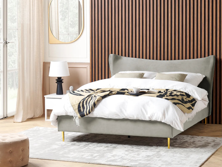 Gray upholstered bed with white bedding and a patterned throw in a bedroom setting.