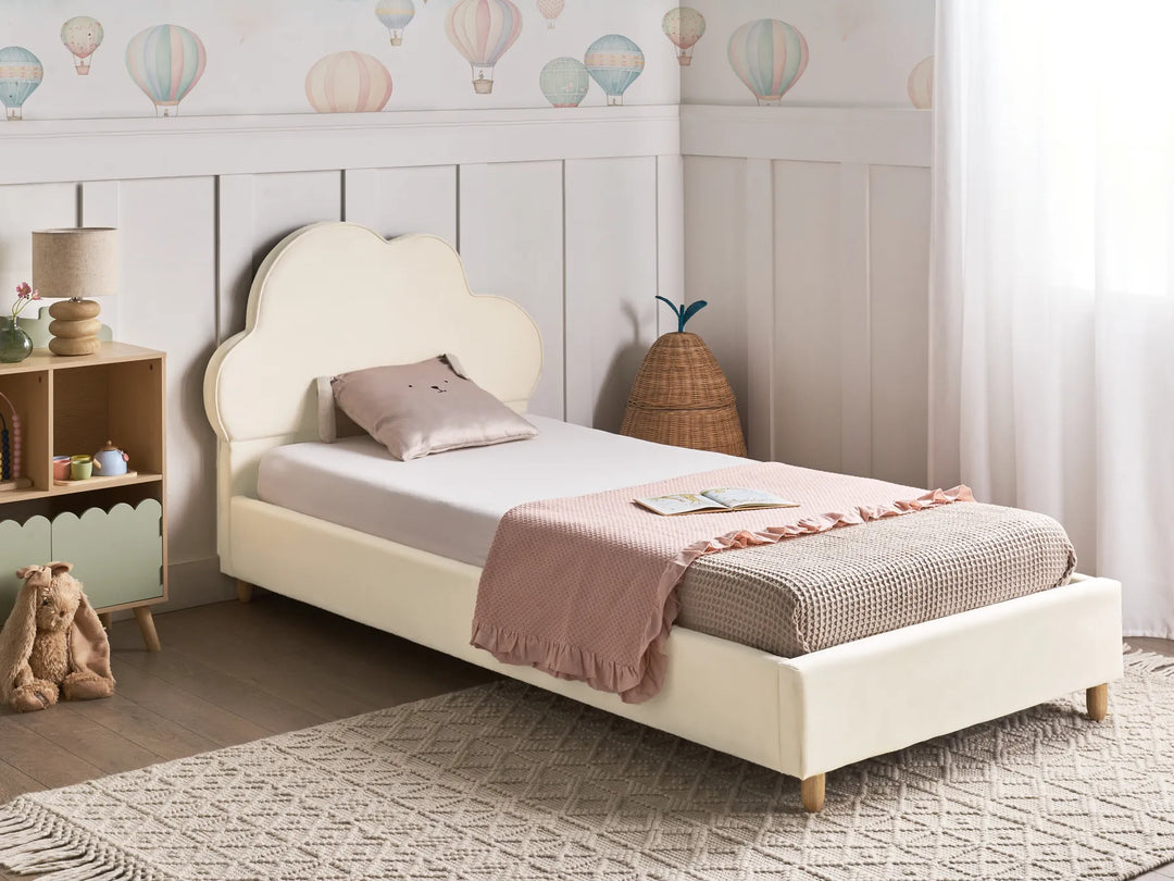 Children's bedroom with a white bed, teddy bear, and colorful balloon wallpaper.
