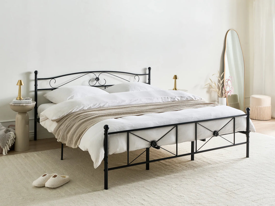 Black metal bed frame with white bedding in a bedroom setting.