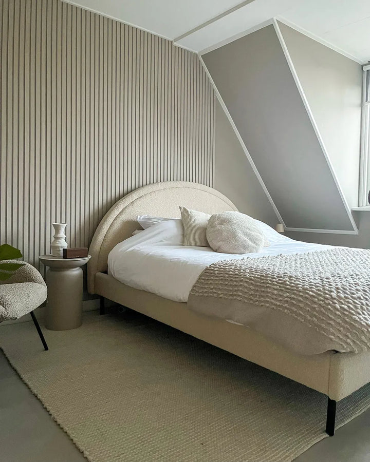 Modern bedroom with a bed, side table, and striped wall.