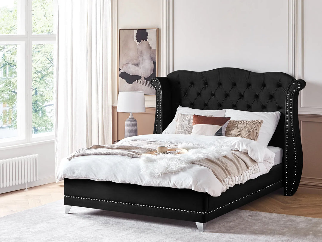 Black upholstered bed with white bedding in a bright bedroom