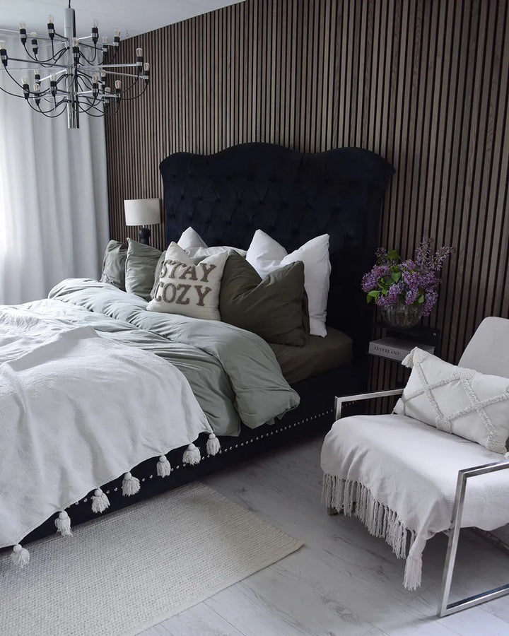 Modern bedroom with a large bed, armchair, and decorative elements.