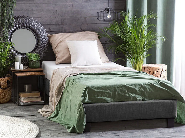 Bedroom with a bed, green blanket, and decorative elements.