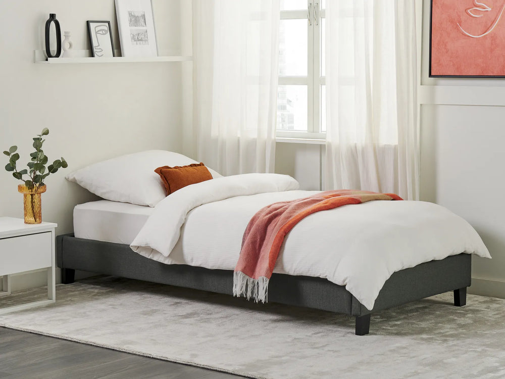 Gray bed frame with white bedding and a red blanket in a bedroom setting.