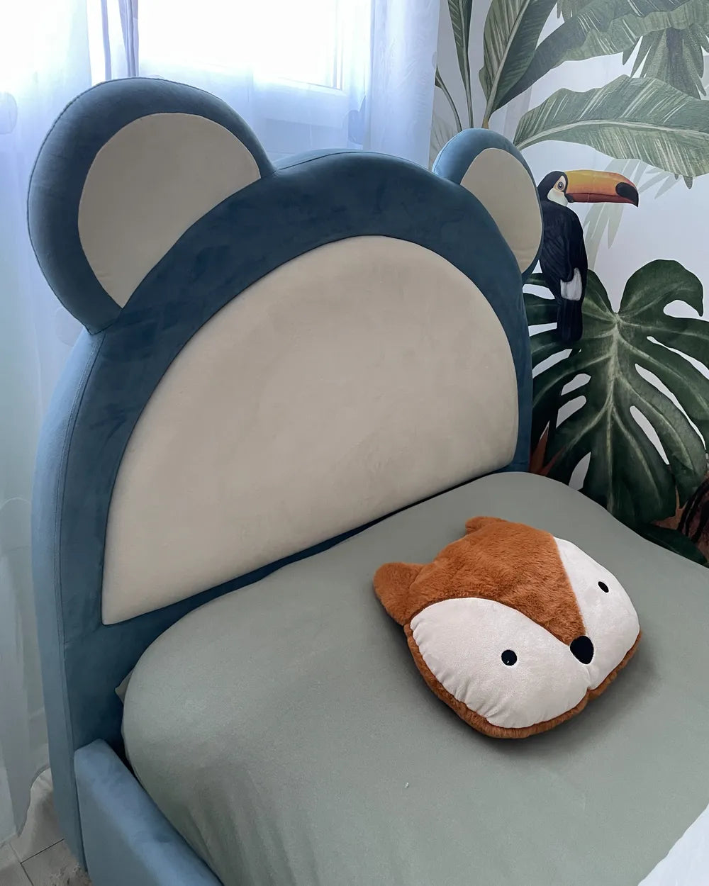 Children's chair with bear ears and a fox-shaped pillow on a light green cushion.