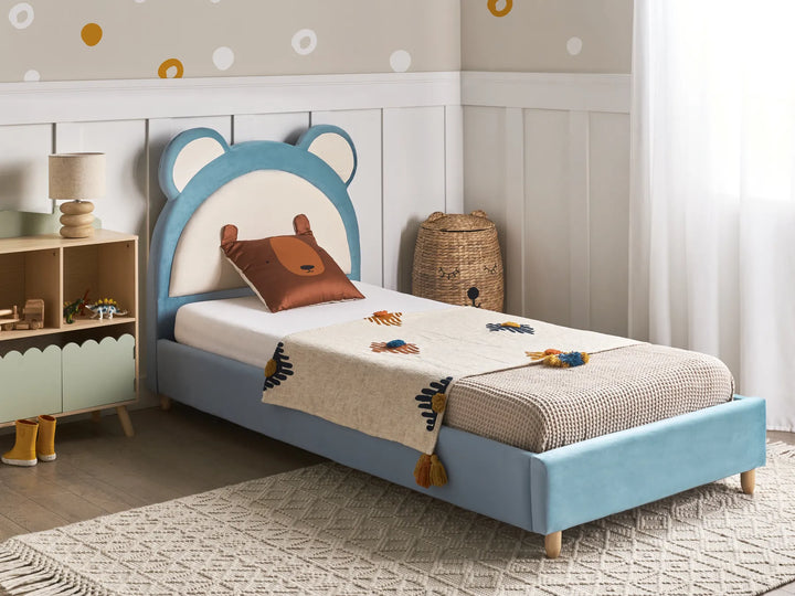 Children's bedroom with a blue bed featuring bear ears, a lamp, and toys.