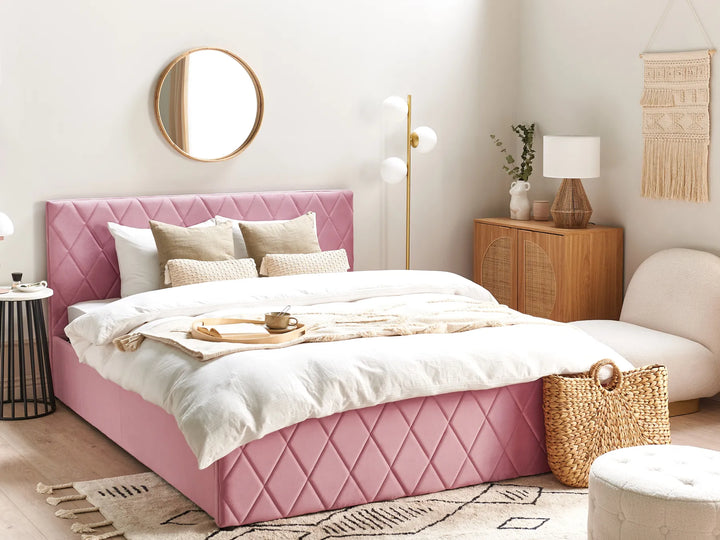 Pink bed in a stylish bedroom with white walls and decorative elements.