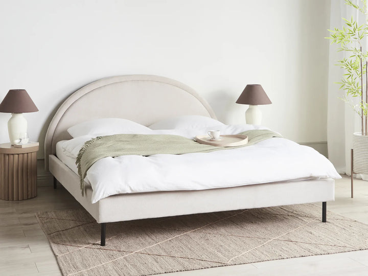 Neatly made bed with white bedding and a green blanket in a bedroom setting.