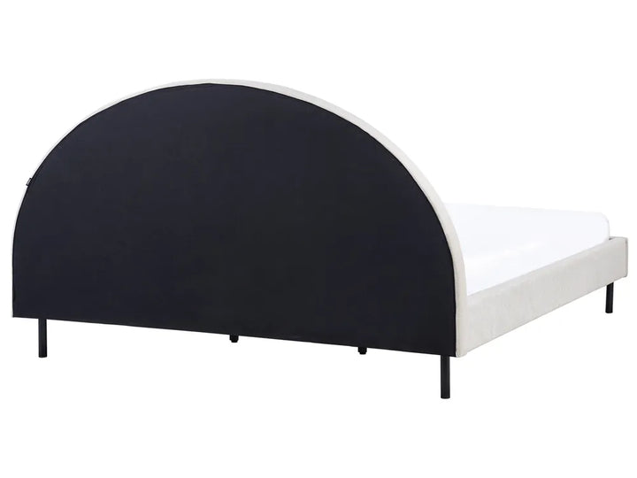 Bed with black curved headboard and white mattress on a white background
