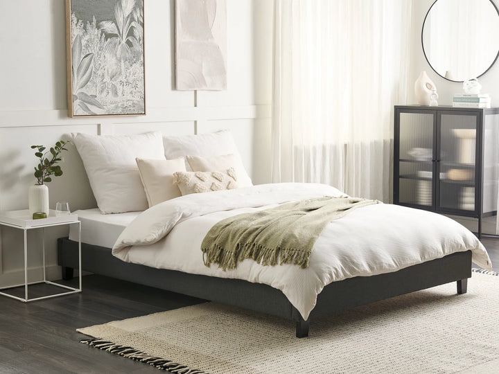 Neatly made bed in a modern bedroom with decor elements.