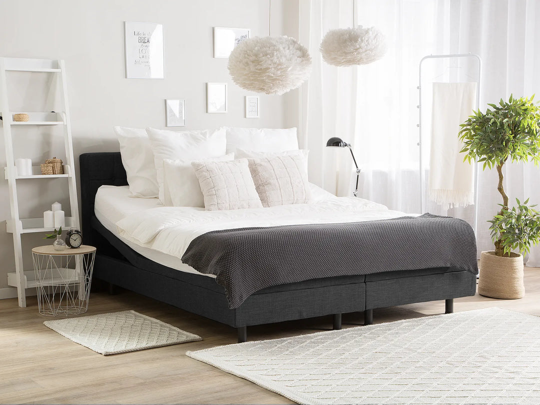 Modern bedroom with a gray bed, white pillows, and decorative elements.