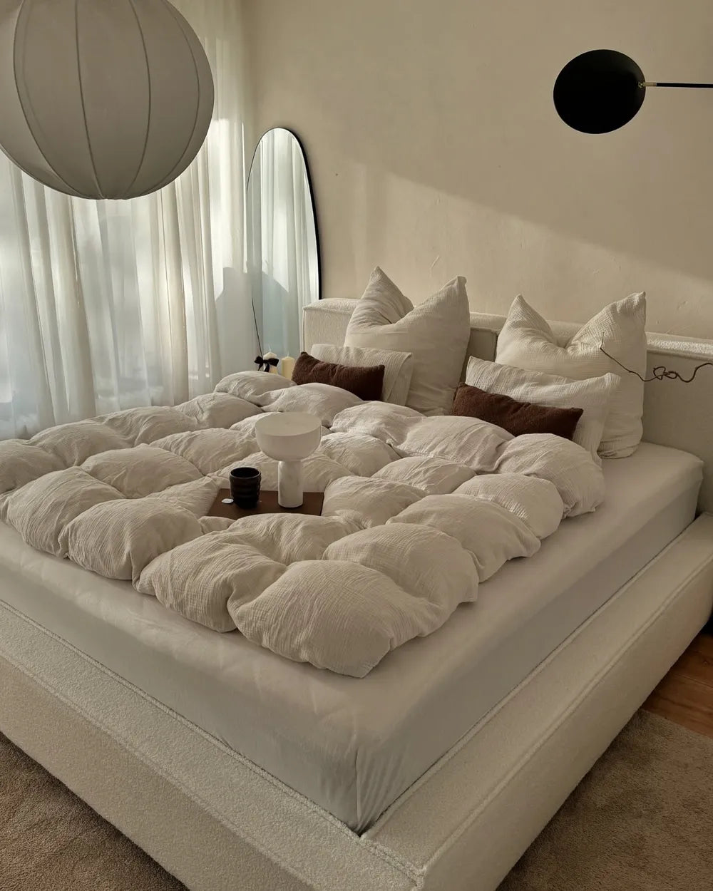 Neatly made bed with white bedding and decorative pillows in a bedroom setting.