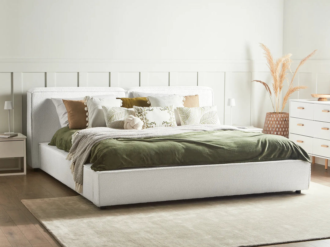 White bed with green bedding in a bedroom setting