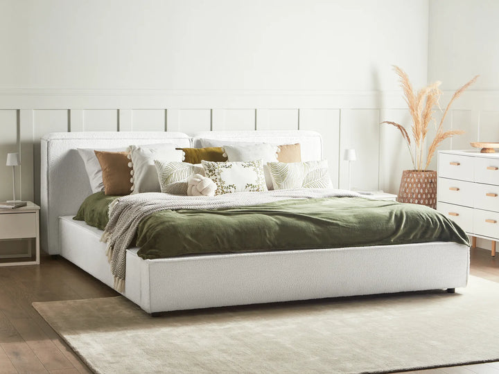 White bed with green bedding in a bedroom setting