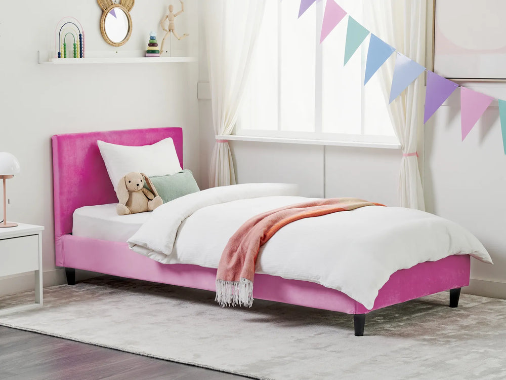 Pink bed with white bedding and a teddy bear in a child's bedroom.