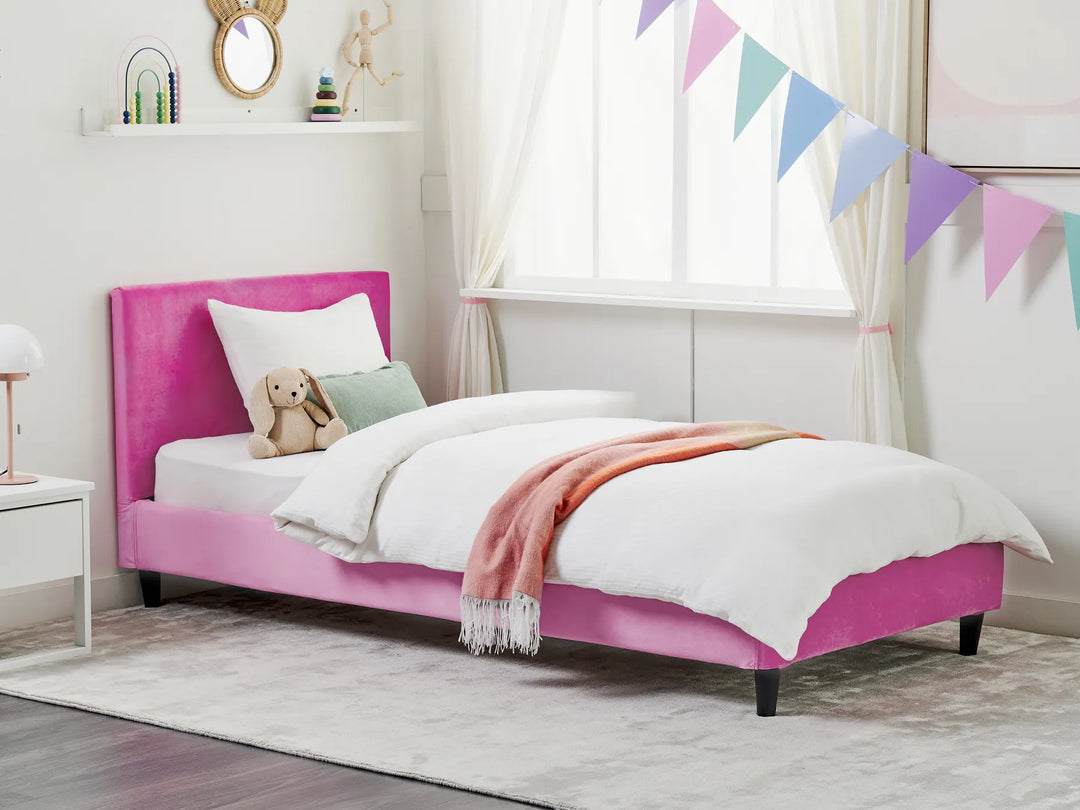 Pink bed with white bedding and a teddy bear in a child's bedroom.