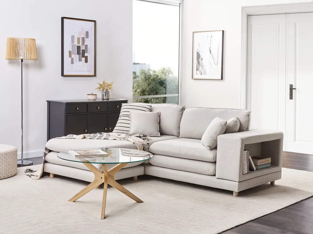 Modern living room with a gray sectional sofa, glass coffee table, and decorative items.
